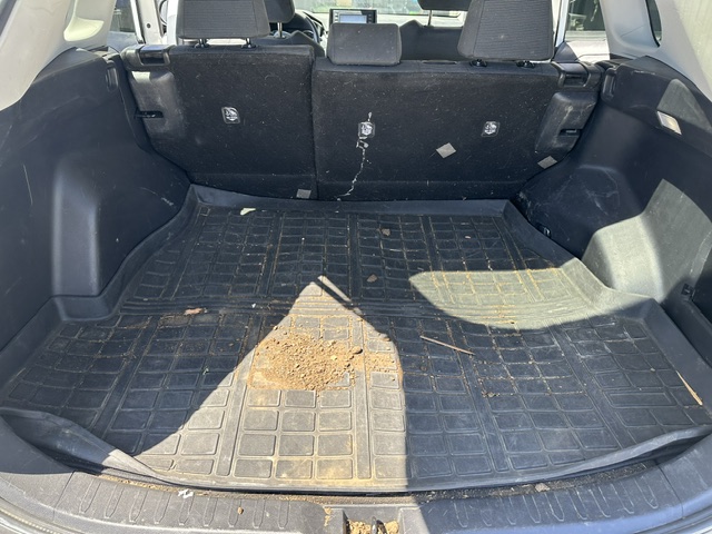 Before interior detailing: dirty cargo area with grit and debris in a white Toyota RAV4