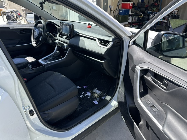 Before interior detailing: trash and dust on the front floor and dash of a white Toyota RAV4