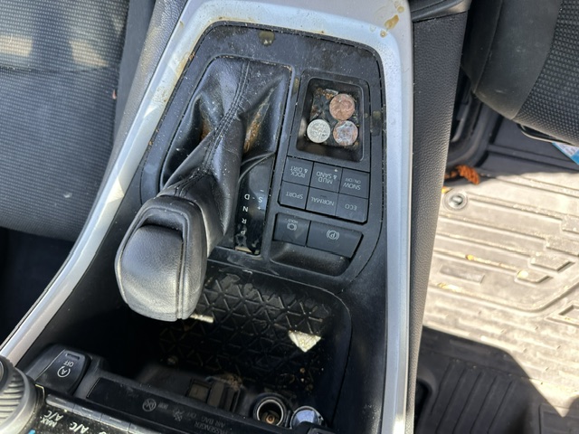 Before interior detailing: sticky center console with grime and coins in a Toyota RAV4